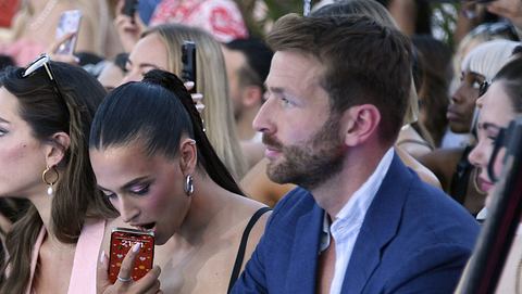 Amira Aly mit Freund Christian Düren auf der Berlin Fashion Week am 02.07.2025. Sie drückt ihr Handy gegen den offenen Mund, er schaut ernst. - Foto:  IMAGO / Marja