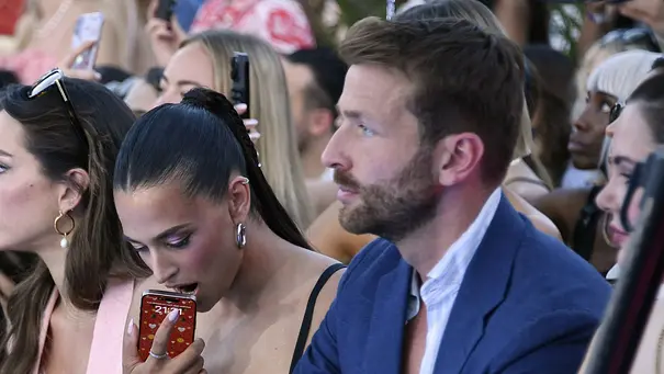 Amira Aly mit Freund Christian Düren auf der Berlin Fashion Week am 02.07.2025. Sie drückt ihr Handy gegen den offenen Mund, er schaut ernst. - Foto:  IMAGO / Marja