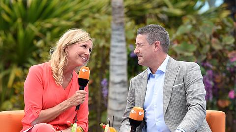 Andrea Kiewel und Joachim Llambi sitzen auf orangefarbenen Sesseln auf der Schwimmbühne. - Foto: ZDF / Sascha Baumann