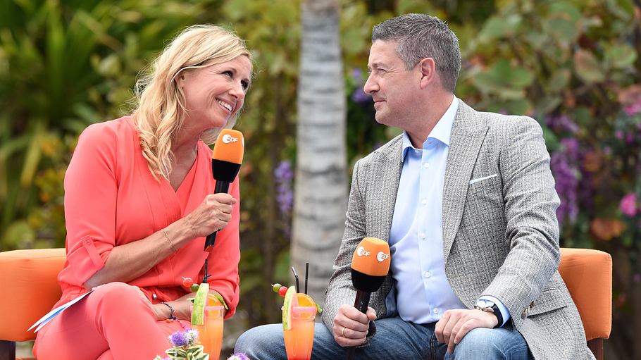 Andrea Kiewel und Joachim Llambi sitzen auf orangefarbenen Sesseln auf der Schwimmbühne.