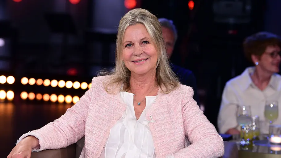 Anja Schüte Schauspielerin Anja Schüte sitzt während einer TV-Aufzeichnung in einem Sessel und lächelt in die Kamera.