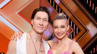 Anna-Carina Woitschack und Evgeny Vinokurov stehen im Lets Dance-Studio nebeneinander und lächeln in die Kamera. - Foto: IMAGO / Panama Pictures