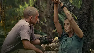Eine Szene aus dem Film Apex auf Netflix: Taron Egerton als Ben sitzt vor Charlize Theron als Sasha, die angekettet ist.  - Foto: Netflix