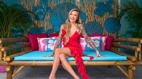 Sophia Thomalla posiert sitzend für AYTO in einem roten Kleid und lächelt - Foto: RTL / Frank Beer