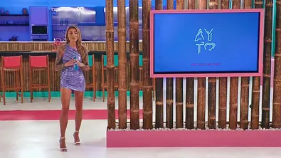 Sophia Thomalla steht in einer Show-Location neben einem großen Bildschirm mit AYTO-Logo; im Hintergrund ist eine Bar zu sehen. - Foto: RTL Sophia Thomalla steht in einer Show-Location neben einem großen Bildschirm mit AYTO-Logo; im Hintergrund ist eine Bar zu sehen. - Foto: RTL