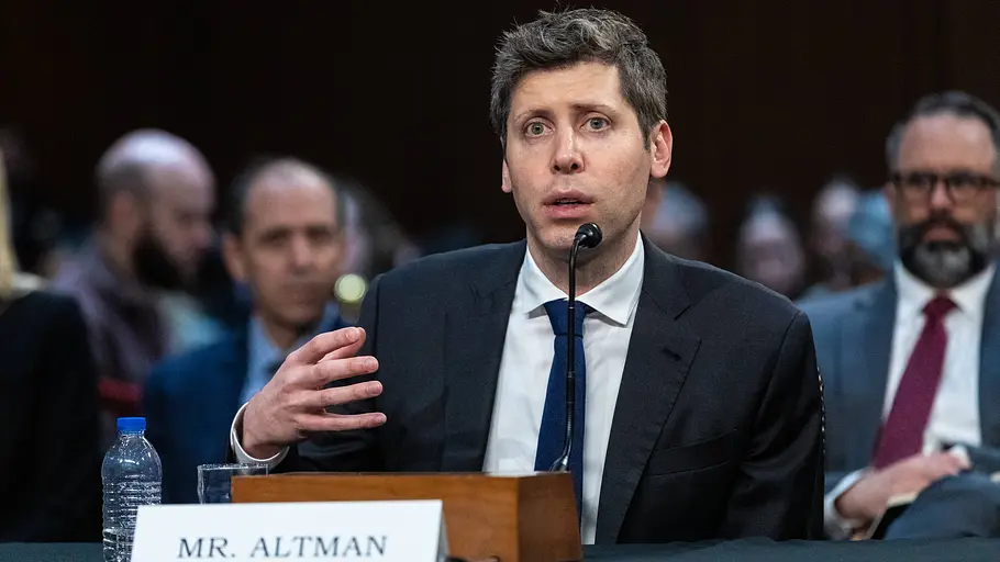 Sam Altman Sam Altman spricht öffentlich an einem Tisch. Vor steht ein Schild mit seinem Namen.