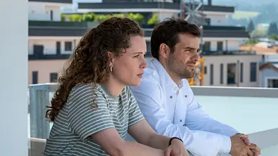 Einfach Elli - Verzeihen: Auf der Dachterrasse der Klinik unterhält sich Dr. Jasper Graf (Lucas Reiber) mit Elli Kempfer (Klara Deutschmann). Beide haben ihre Arme auf das Geländer gestützt. Beide machen einen besorgten Gesichtsausdruck. - Foto: ZDF/Susanne Bernhard