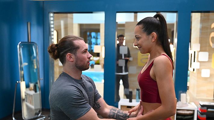 Charlie und Milan schauen sich tief in die Augen, während Deniz im Hintergrund zu sehen ist. - Foto: RTL / Julia Feldhagen
