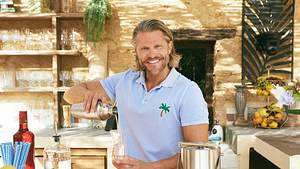 Paul Janke als Barkeeper bei Bachelor in Paradise, lächelt in die Kamera während er Drinks mixt - Foto: RTL