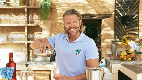 Paul Janke als Barkeeper bei Bachelor in Paradise, lächelt in die Kamera während er Drinks mixt - Foto: RTL