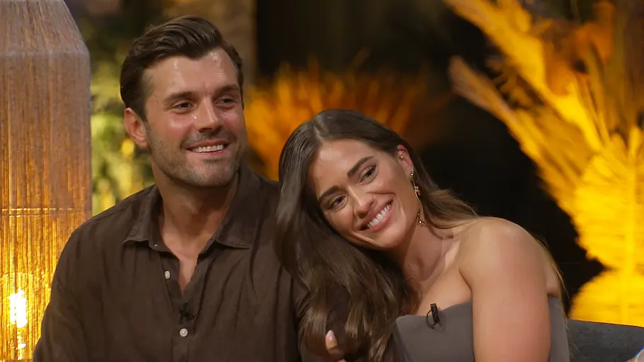 Tim und Vivi Tim und Vivi sitzen eng beieinander auf einem Sofa. Vivi lehnt ihren Kopf an die Schulter von Tim, während beide glücklich in dieselbe Richtung blicken.