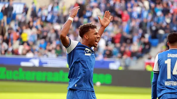 Bambase Conte jubelt im blauen Fußballtrikot mit erhobenen Armen. Hinter ihm stehen Zuschauer auf der Tribüne. - Foto: IMAGO / Sportfoto Rudel Bambase Conte jubelt im blauen Fußballtrikot mit erhobenen Armen. Hinter ihm stehen Zuschauer auf der Tribüne. - Foto: IMAGO / Sportfoto Rudel