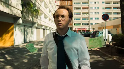 Michelangelo Fortuzzi steht in einem Innenhof. Vor fliegen 100-Euro-Scheine. - Foto: HBO Max/Anne Wilk