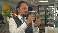 „Bares für Rares“-Händler Wolfgang Pauritsch begutachtet in einem Antiquitätengeschäft aufmerksam einen silberfarbenen Zigarettenhalter mit passendem Etui. Im Hintergrund sind Vitrinen mit Porzellan und weiteren Sammlerstücken zu sehen. - Foto: ZDF/Guido Engels „Bares für Rares“-Händler Wolfgang Pauritsch begutachtet in einem Antiquitätengeschäft aufmerksam einen silberfarbenen Zigarettenhalter mit passendem Etui. Im Hintergrund sind Vitrinen mit Porzellan und weiteren Sammlerstücken zu sehen. - Foto: ZDF/Guido Engels