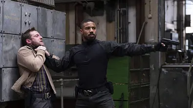 Michael B. Jordan hält eine Waffe in der Hand und drückt eine andere Person gegen die Wand.  - Foto:  IMAGO / Cinema Publishers Collection