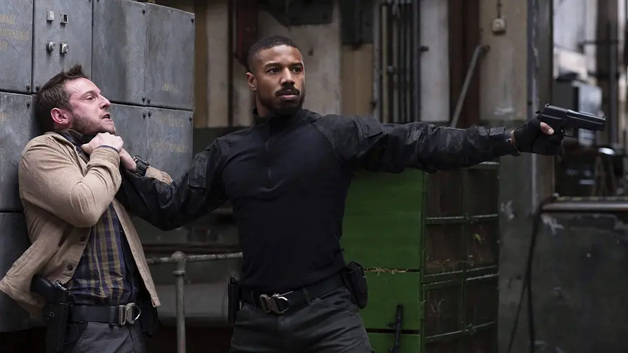 Michael B. Jordan Michael B. Jordan hält eine Waffe in der Hand und drückt eine andere Person gegen die Wand.