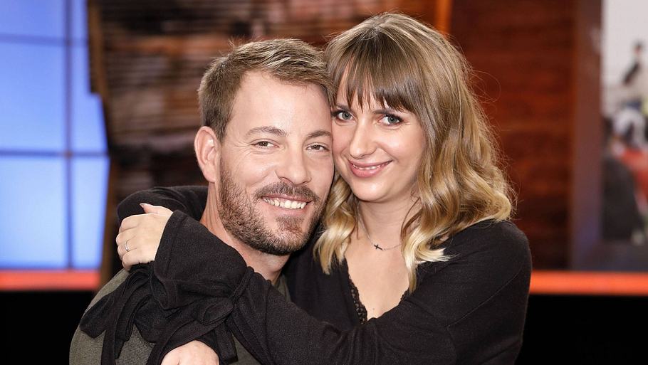 Anna und Gerald Heiser halten sich in den Armen und lächeln in die Kamera.
