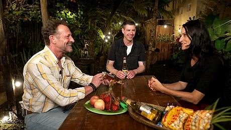 Die „Bauer sucht Frau International“-Kandidaten Carmen, Patrick und Sven sitzen gemeinsam am Tisch und lachen. - Foto: RTL