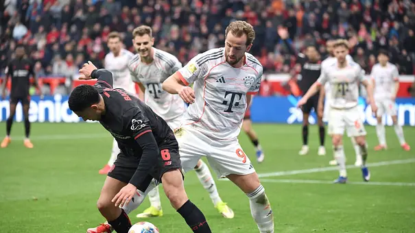 Harry Kane und ein Spieler von Bayer 04 Leverkusen kämpfen um den Ball - Foto: Imago Images
