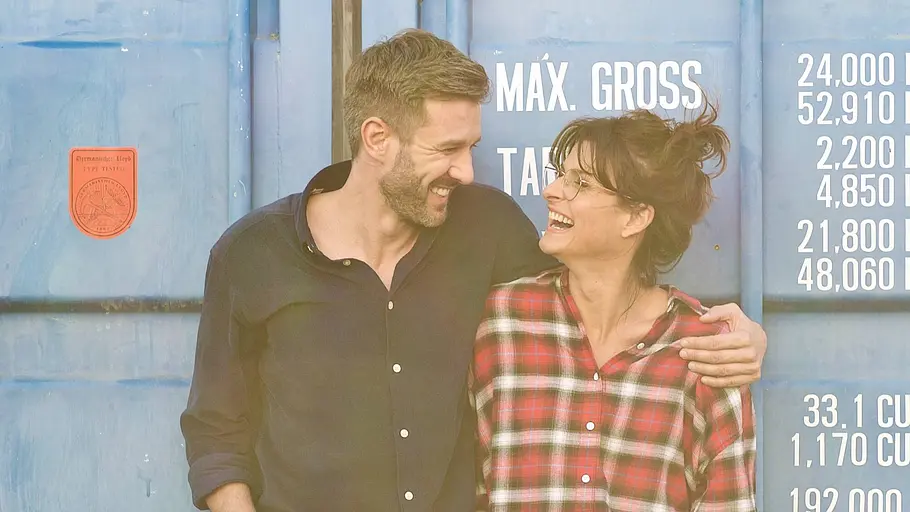 Promi BB-Kritik Jochen Schropp & Marlene Lufen Jochen Schropp legt vor einem blauen Container den Arm um Marlene Lufen. Beide schauen einander lachend an.