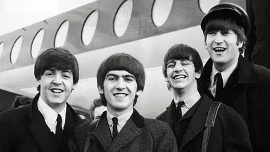Die Beatles stehen vor einem Flugzeug und lachen in die Kamera. - Foto: IMAGO / Cinema Publishers Collection