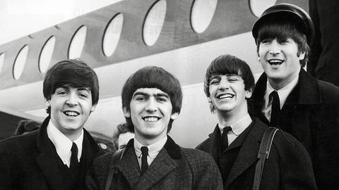 Die Beatles stehen vor einem Flugzeug und lachen in die Kamera. - Foto: IMAGO / Cinema Publishers Collection