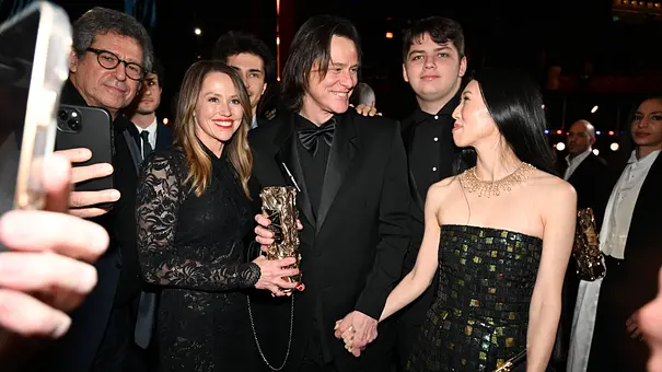 Jim Carrey posiert mit Jane, Jackson und Min Ah in festlicher Kleidung. Jane hält eine goldene Trophäe, Min Ah seine Hand. - Foto: IMAGO / Starface
