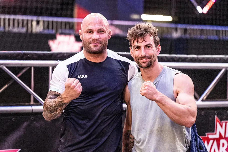 Benni Grams ist Teilnehmer bei Ninja Warrior Germany 2026 Christian Jungwirth (links) und Benni Grams (rechts) stehen in Sportkleidung nebeneinander und halten je eine Faust vor die Brust.