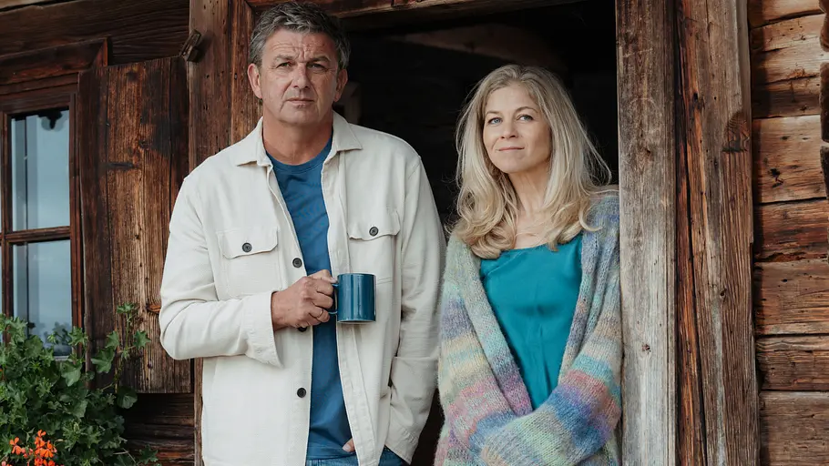 Wie werden Martin und Karin auf die Rückkehr reagieren? Martin und Karin stehen angelehnt an der Tür.