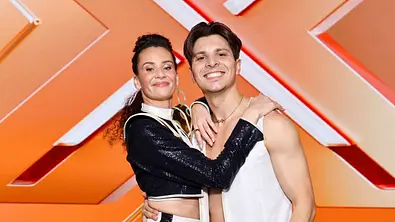 Betty Taube und Alexandru Ionel stehen in Tanzmontur vor einem orangenen Hintergrund.  - Foto:  IMAGO / Panama Pictures
