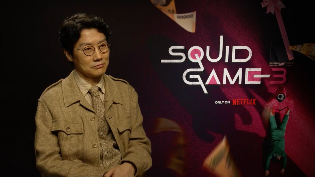 Hwang Dong-hyuk Dong-Hyuk vor dem „Squid Game“-Logo mit einem sanften Lächeln im Gesicht