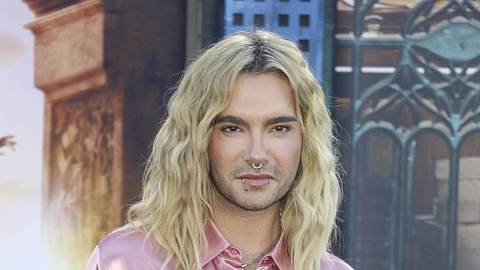 Bill Kaulitz in einer rosafarbenen Seidenbluse und blondierten, langen Haaren. Er schaut ernst und direkt in die Kamera. - Foto:  IMAGO / imagebroker