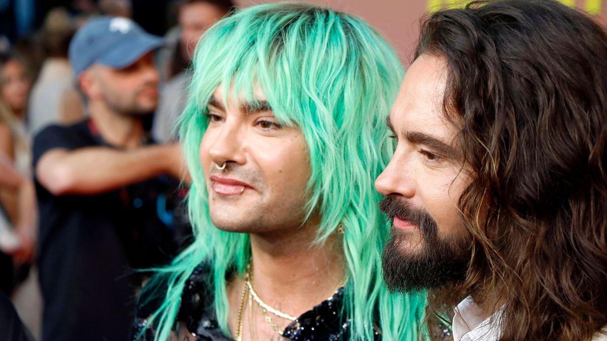 Bill und Tom Kaulitz stehen nebeneinander im Seitenprofil, sie schauen nach links. 