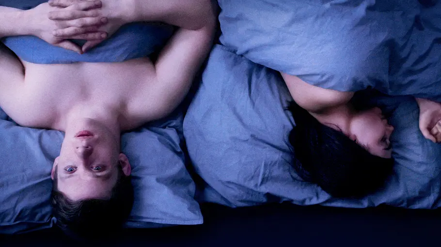 Black Mirror Ein Mann und eine Frau liegen in getrennten Betthälften unter blauer Bettwäsche. Während er wach zur Decke blickt, hat sie sich von ihm abgewandt – das Poster zeigt die „Black Mirror“-Folge „Hang the DJ“.