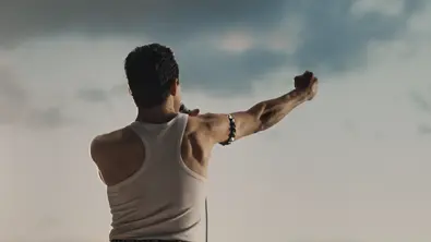 Freddy Mercury steht auf einer Bühne und hält seine Faust in die Lauft. Man sieht nur seinen Rücken. - Foto: 20th Century Fox