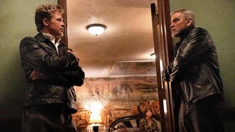 George Clooney und Brad Pitt im Film Wolfs stehen in einer Szene, Arme verschrenkt, neben einer Tür. - Foto: IMAGO / ZUMA Press