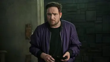 Frederick Lau steht in einer lila Bomberjacke mit einem schwarzen Shirt in einem dunklen Raum. Hinter ist eine Anthrazit-farbende Mauer. - Foto: Sasha Ostrov / Netflix Frederick Lau steht in einer lila Bomberjacke mit einem schwarzen Shirt in einem dunklen Raum. Hinter ist eine Anthrazit-farbende Mauer. - Foto: Sasha Ostrov / Netflix