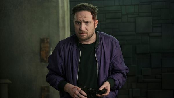 Frederick Lau steht in einer lila Bomberjacke mit einem schwarzen Shirt in einem dunklen Raum. Hinter ist eine Anthrazit-farbende Mauer. - Foto: Sasha Ostrov / Netflix