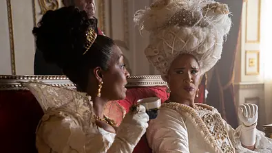 Adjoa Andoh als Lady Danbury und Golda Rosheuvel als Queen Charlotte sind festlich gekleidet. Sie unterhalten sich und trinken Tee. - Foto: Liam Daniel/Netflix © 2022 Adjoa Andoh als Lady Danbury und Golda Rosheuvel als Queen Charlotte sind festlich gekleidet. Sie unterhalten sich und trinken Tee. - Foto: Liam Daniel/Netflix © 2022