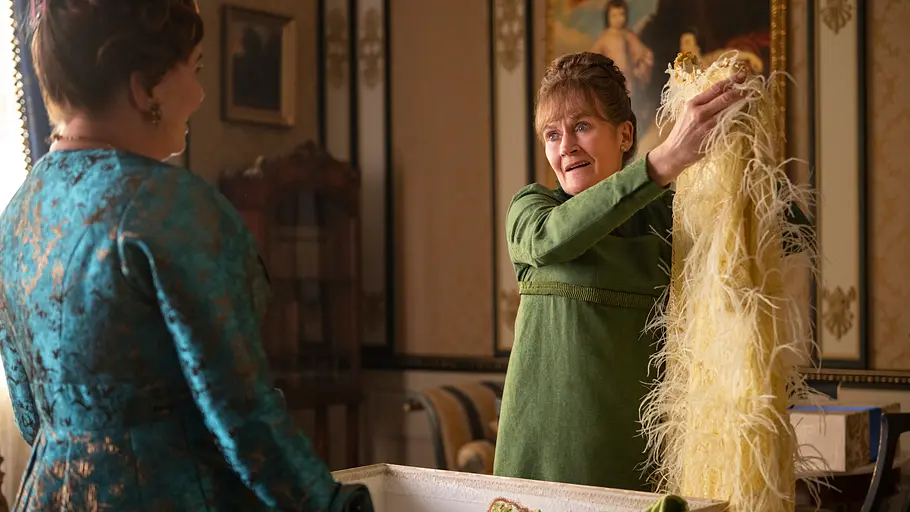 „Bridgerton“ Staffel 4 Die ehemalige Haushälterin der Featheringtons, Varley, hält fragend ein Kleid in die Höhe.
