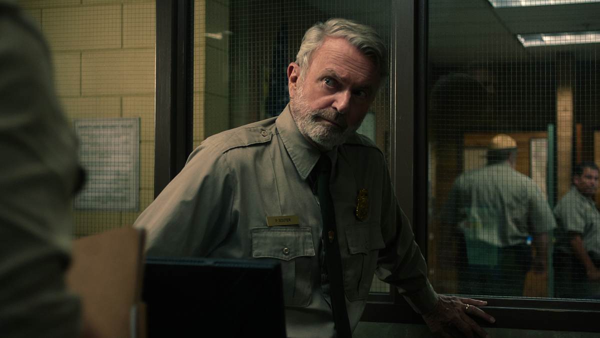 Captain Paul Souter entgeht einer langen Haftstrafe. Sam Neill als Paul Souter. Er schaut fragend die Person vor sich an, sein halbes Gesicht liegt im Schatten.