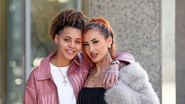 Carina und Chika stehen eng umarmt vor einem Gebäude und lächeln in die Kamera. - Foto: IMAGO / Gartner Carina und Chika stehen eng umarmt vor einem Gebäude und lächeln in die Kamera. - Foto: IMAGO / Gartner
