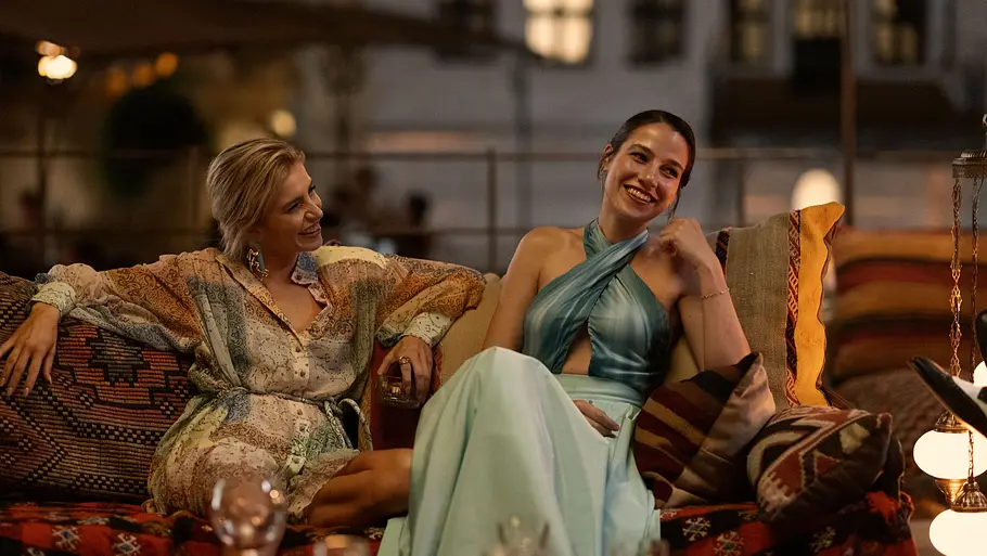 Caro Daur und Beritan Balcı als Mavi und Nora. Szenen-Bild aus She Said Maybe: Caro Daur und Beritan Balcı lachen gemeinsam auf dem Sofa.