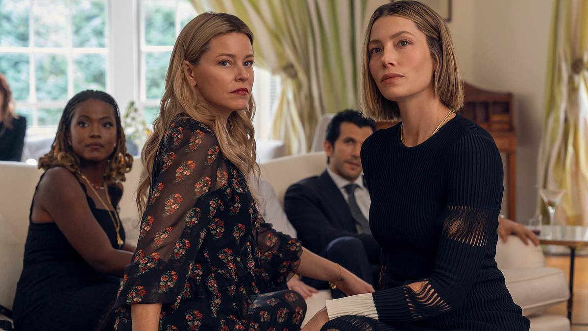 Cassandra Freeman (Janie), Elizabeth Banks (Nicky), Gabriel Sloyer (Jake) und Jessica Biel (Chloe) in „Die perfekte Schwester“. Cassandra Freeman (Janie), Elizabeth Banks (Nicky), Gabriel Sloyer (Jake) und Jessica Biel (Chloe) aus „Die perfekte Schwester“ sitzen im Wohnzimmer auf dem Sofa, alle schauen in dieselbe Richtung.