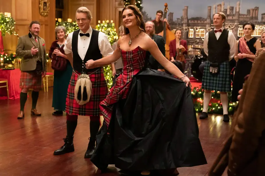 Castle for Christmas Cary Elwes als Myles und Brooke Shields als Sophie in A Castle For Christmas. Sie macht einen Knicks und sie halten Händchen. Sie tragen schottische Ballkleidung.