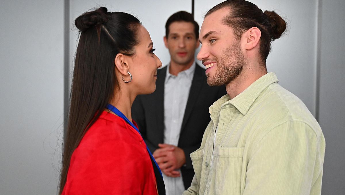 Charlie und Milans Glück wird bedroht. Charlie und Milan lächeln sich glücklich an, im Hintergrund ist Deniz zu sehen.