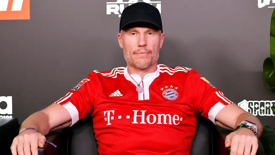 Fußballspieler Christian Lell bei Fame Fighting International in Bayern-Trikot und mit Mütze. 