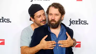 Christian Ulmen steht mit Fahri Yardim vor einer Fotowand für „jerks.“. Yardim umarmt ihn von hinten.  - Foto: IMAGO / Berlinfoto