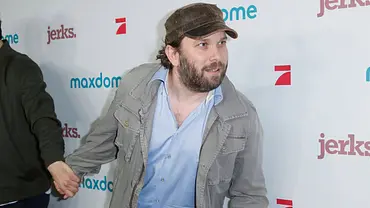 Christian Ulmen beugt sich auf dem Roten Teppich fragend zur Seite, während er jemanden an der Hand hat.  - Foto: IMAGO / VISTAPRESS