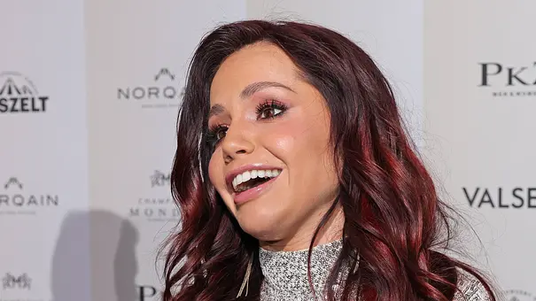 Christina Hänni gibt ein Interview auf dem Red Carpet, sie trägt ein Glitzer-Kleid und offene Haare. - Foto: IMAGO / Bildagentur Monn